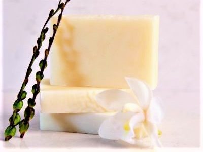 manuka honey soap three in a stack with orchid and plant on marble background