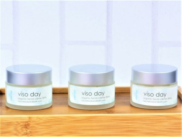 Viso day face moisturiser in glass pots on wood with white brick background