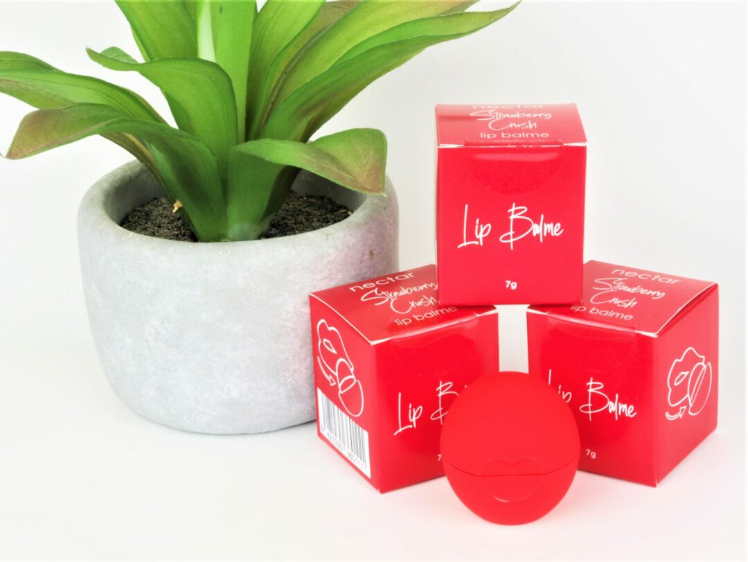 red organic lip balm ball with boxes and plant