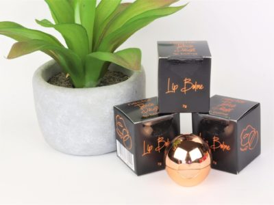 rose gold organic lip balm ball with boxes and plant