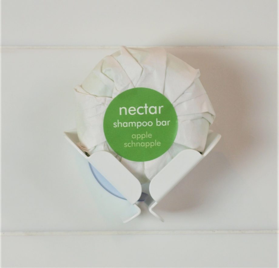 shampoo bar with green lable in white block dock attached to white tiled wall