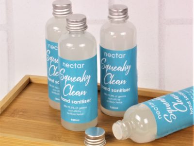 squeaky clean hand sanitisers group of bottles with one lying down with lid off on wood