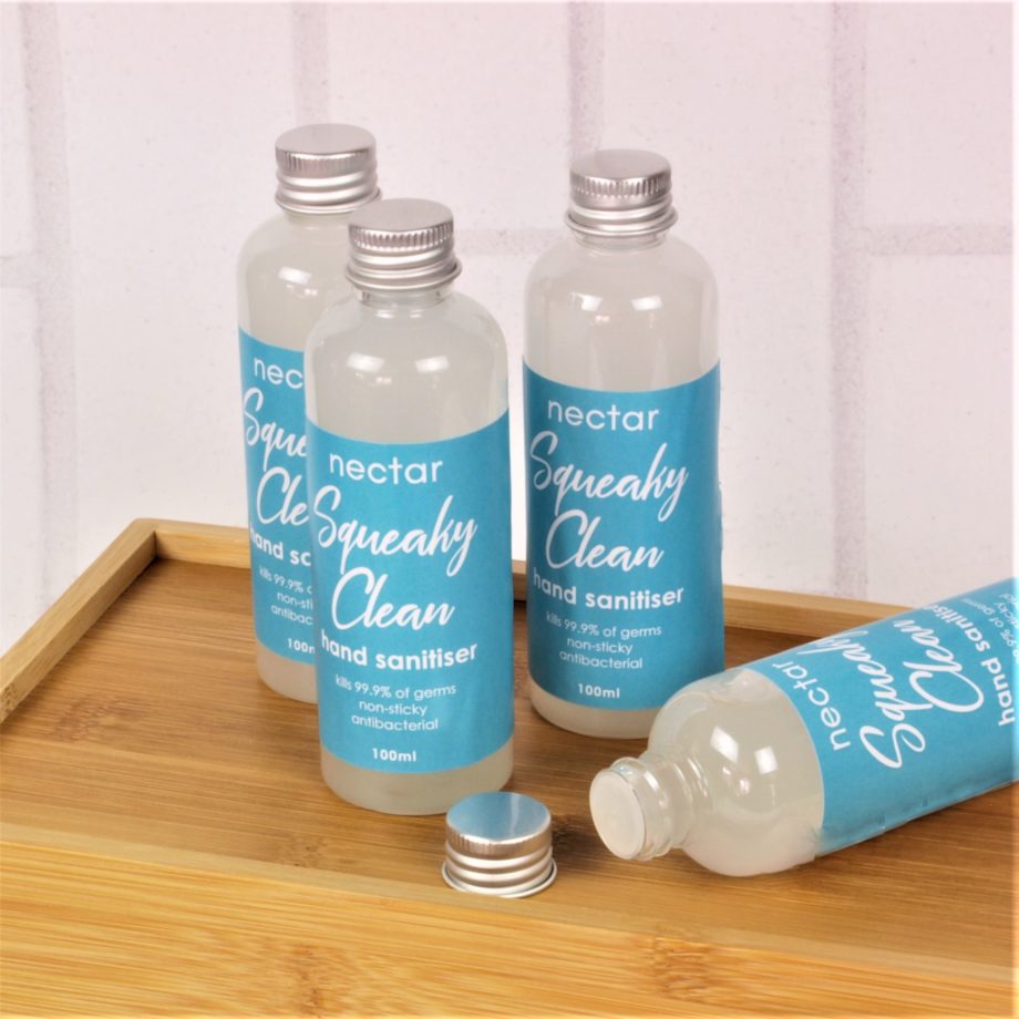 squeaky clean hand sanitisers group of bottles with one lying down with lid off on wood